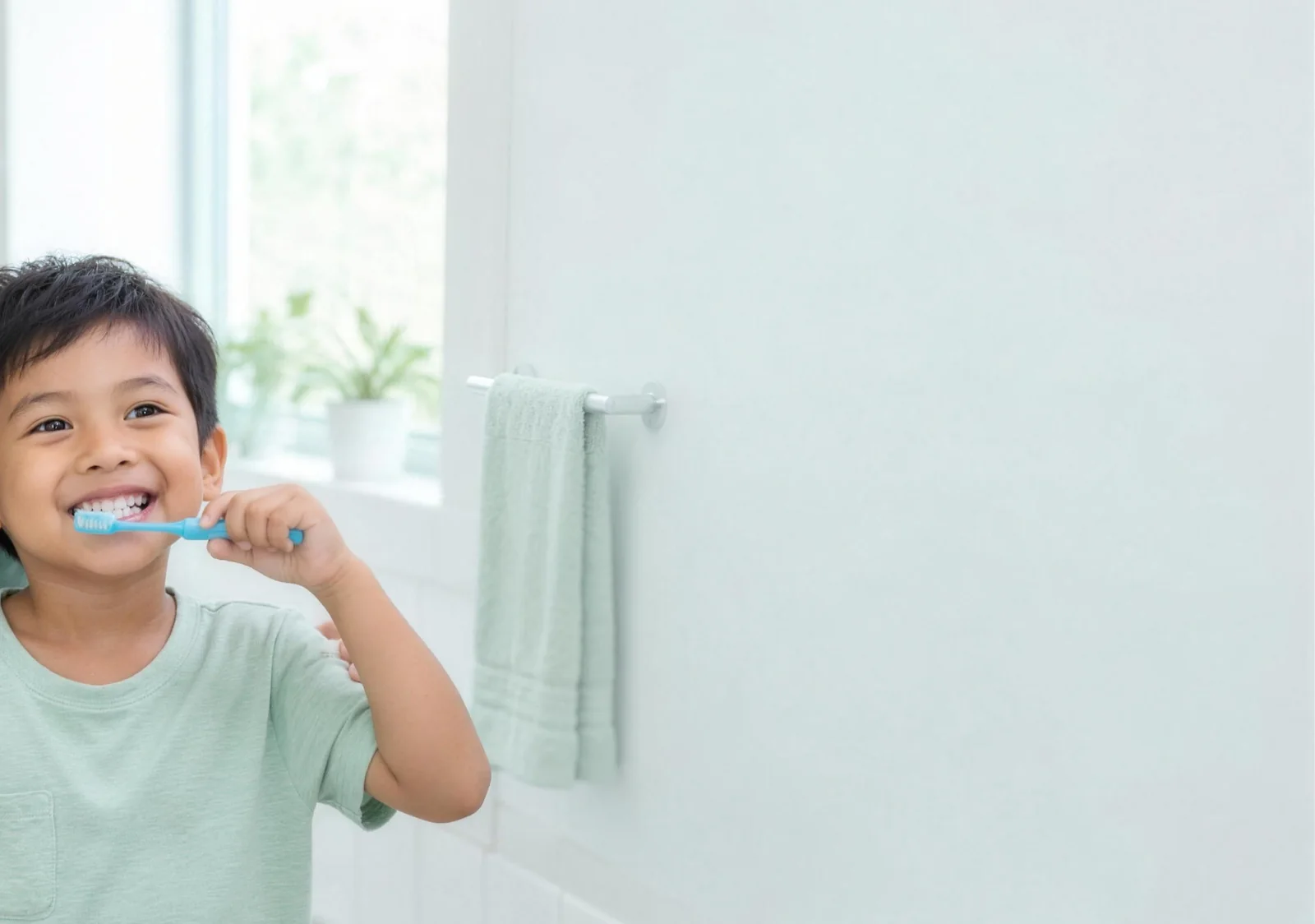 Young boy smiling while brushing his teeth
